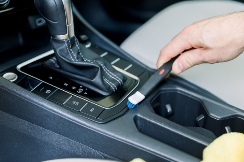 person cleaning interior console of a car